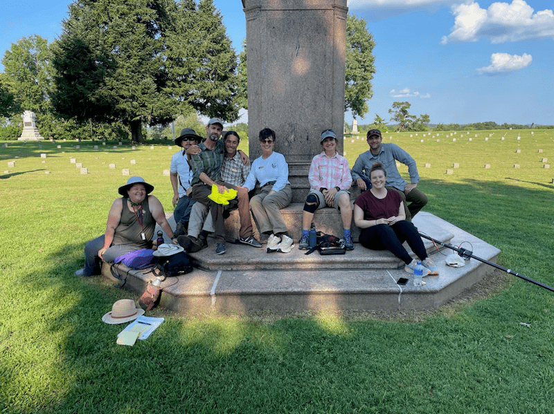 Crew sitting around a cemetery monument